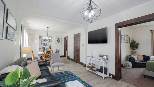 A spacious living room with a sofa, armchairs, a coffee table, and a TV mounted on the wall. There is a dining area in the background with a table and chairs. - 3 Blocks from Beach house 1 BDRM full bath 4 min to downtown,sleeps 4 (Sheboygan)