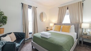 A hotel room with a bed, a chair, a bedside table with lamps, a mirror, and a window with curtains. - 3 Blocks from Beach house 1 BDRM full bath 4 min to downtown,sleeps 4 (Sheboygan)