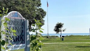 A sign for General King City of Sheboygan with a flag and a view of the water in the background. - 3 Blocks from Beach house 1 BDRM full bath 4 min to downtown,sleeps 4 (Sheboygan)