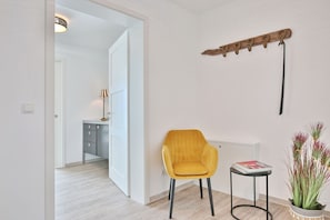 Um interior moderno com uma cadeira amarela, uma mesinha e um objeto decorativo de madeira na parede.