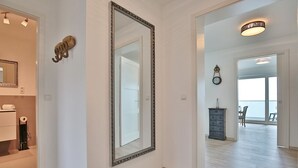 A hallway with a large mirror, a wooden floor, a dresser, and a view of a balcony. - Haus Sommertraum, Appartement 5 "sonnensegel" - Haus Sommertraum (Scharbeutz)