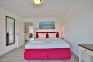 Una camera da letto con un letto grande, un quadro al muro e uno specchio a sinistra.