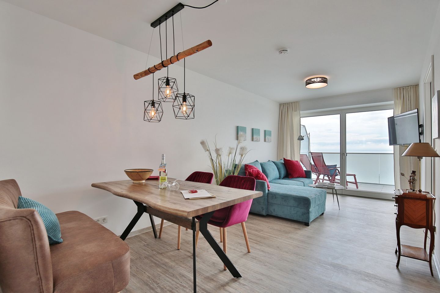 Ein modernes Wohnzimmer mit einem Holzesstisch, einer Couch und einem Balkon mit Fernseher.