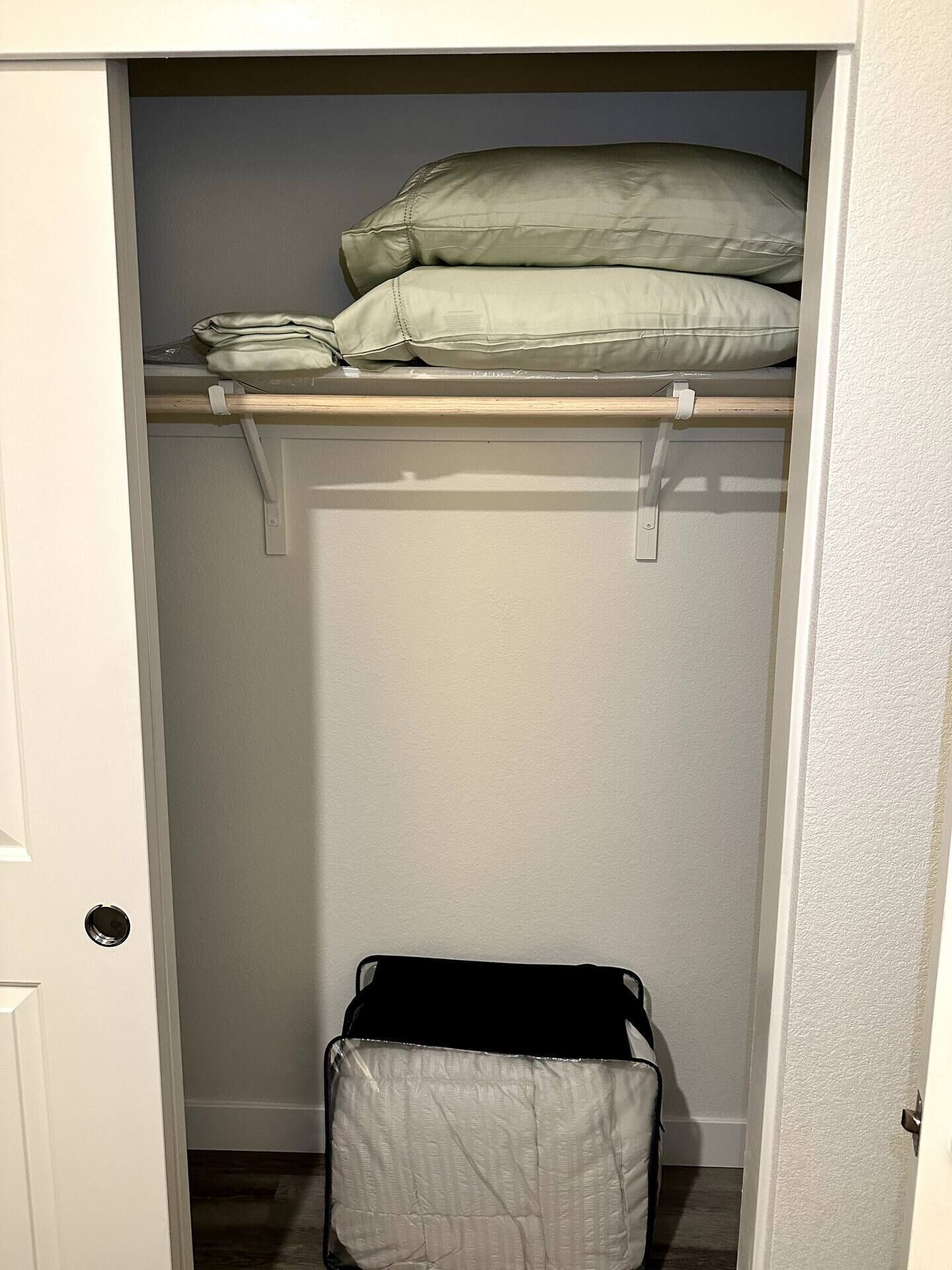 A closet with a hanging rod and a storage bin.