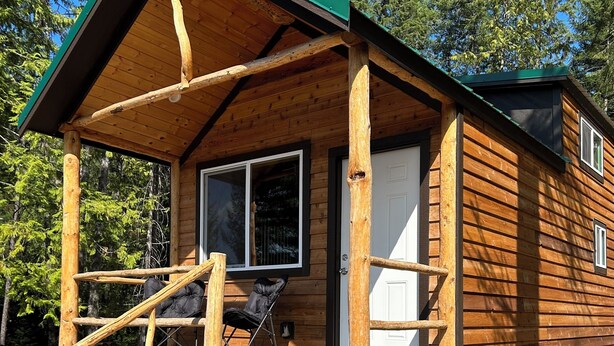 Une cabane en bois avec une véranda, une porte et une fenêtre.
