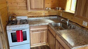 Une cuisine de taille réduite, dotée de meubles en bois, d’une cuisinière blanche, d’un évier et de plans de travail en granit.