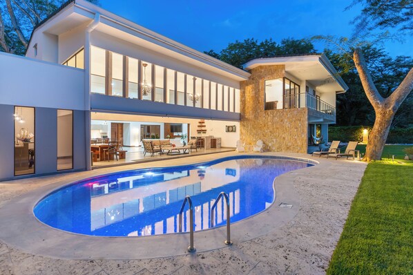 A modern house with a swimming pool, large windows, and outdoor furniture.