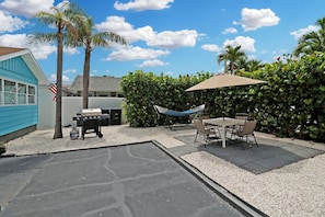Enjoy al fresco dining and relaxation in this serene backyard patio, featuring a barbecue grill, hammock, and dining table.