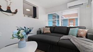 Una sala de estar moderna con un sofá gris oscuro, una mesa de centro blanca y un jarrón con flores.