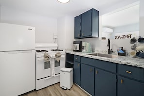 Compact kitchen with a refrigerator, stove, oven, sink, and coffee maker.