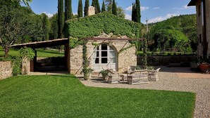 Een stenen cottage met een kleine tuin, een houten pergola en een stenen muur.