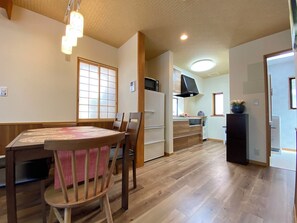 A dining area with a round table and chairs, a kitchen in the background, and a wooden floor. - N9#Good Location + Clean Room! in Shinjuku (新宿区)