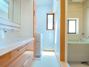 A narrow, modern bathroom with a wooden vanity, a small window, and a bathtub. - N9#Good Location + Clean Room! in Shinjuku (新宿区)