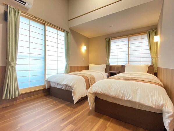 A hotel room with two beds, wooden flooring, and large windows with curtains. - N9#Good Location + Clean Room! in Shinjuku (新宿区)