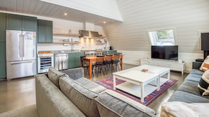 A modern kitchen with a dining area, a living room with a sofa, and a TV. - Saddleback - Parmachenee A-Frame #1 - SkiFrame (Sandy River Plantation)