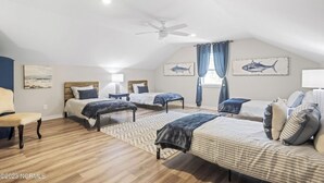 A spacious bedroom with two beds, a ceiling fan, and nautical-themed wall art. - Only TWO MILES to the beach! Custom bungalow. Fenced-in yard! (Ocean Isle Beach)