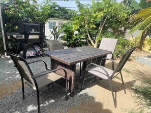 A patio area with a table and four chairs, surrounded by greenery and a barbecue grill. - Don Julio’s getaway home.<br>A nice place to relax next to mother’s nature <br> (luquillo)