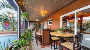 An indoor dining area with a pool view, wooden ceiling, and various plants. - BOHO Paradise, KING Bed, POOL, 1 month+LONG Term Stays,PET FRIENDLY (Pompano Beach)