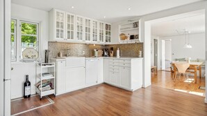 A modern kitchen with white cabinets, a tiled backsplash, and a wooden floor. - 2 bedroom awesome home in Haarby (Haarby)