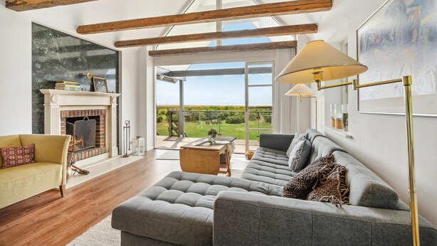 A spacious living room with a fireplace, a large sofa, and a view of the outdoors. - 2 bedroom awesome home in Haarby (Haarby)