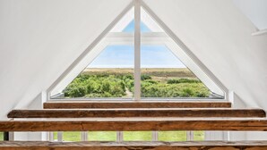 A room with a large triangular window offering a view of a grassy landscape and a body of water. - 2 bedroom awesome home in Haarby (Haarby)