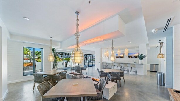 A spacious dining area with high ceilings, modern lighting fixtures, and a view of the outdoor patio.