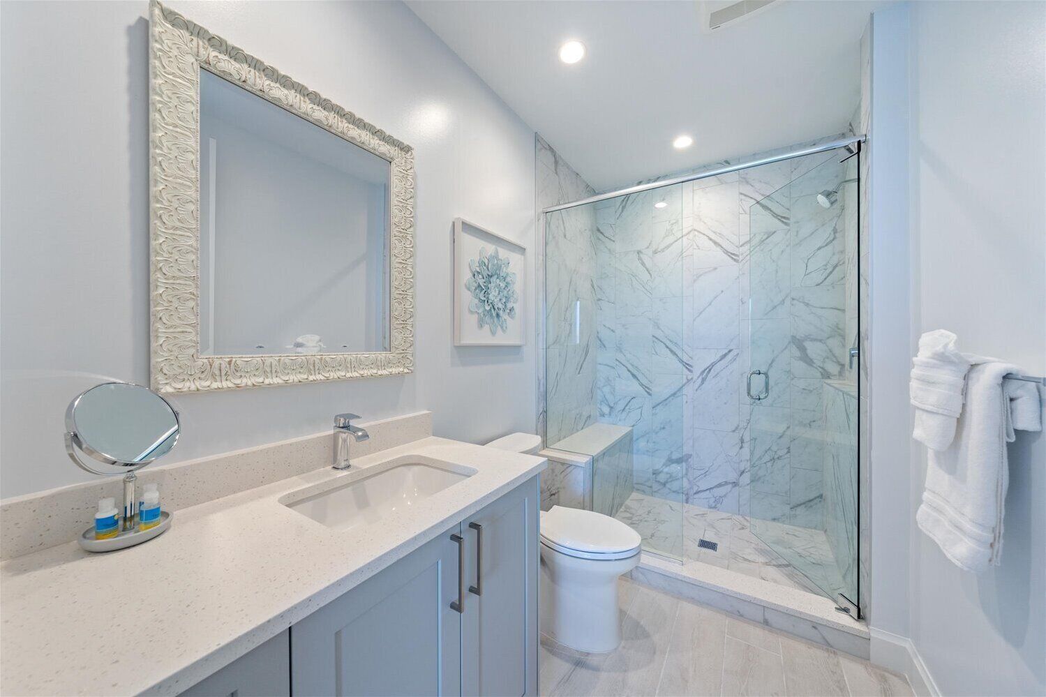 Un baño moderno con un espejo grande, dos lavamanos, un inodoro y una ducha con cerramiento de vidrio.