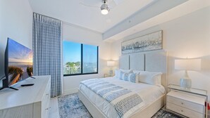 A modern bedroom with a large bed, a TV, and a view of the outdoors.