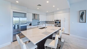 A modern kitchen with white cabinetry, stainless steel appliances, and a central island with seating.