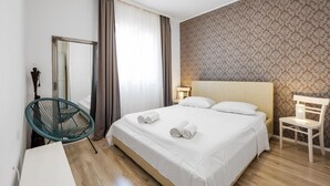 Una habitación de hotel con una cama grande, una silla, una lámpara y un espejo.