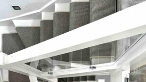 A modern interior with a central open space, white structural elements, and a patterned floor.
