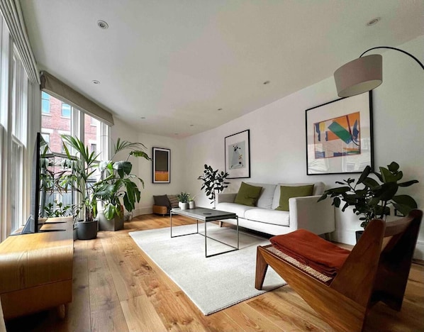 A modern living room with a sofa, coffee table, and plants. - Modern Retreat in the Heart of Shoreditch (London)