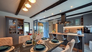 A modern kitchen with dark cabinetry, a central island, and a dining area with a dark marble table and cushioned chairs. - Nice home in Stubicke Toplice with sauna (Stubicke Toplice)