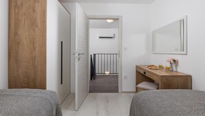 A hotel room with two beds, a wooden wardrobe, a desk with a mirror, and a small table with breakfast items. - Lovely home in Kraljevica with house sea view (Kraljevica)