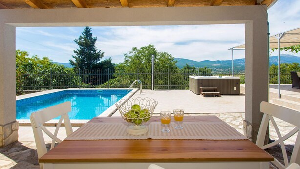 A covered outdoor area with a pool, a table with chairs, and a view of mountains. - Gorgeous home in Bajagic (Bajagic)