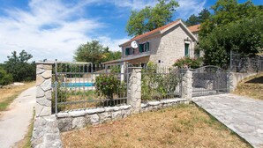 A stone house with a pool, surrounded by a metal fence and stone walls. - Gorgeous home in Bajagic (Bajagic)