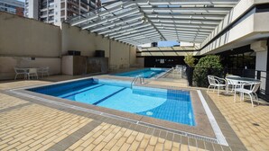 A rooftop swimming pool with two separate sections, surrounded by a tiled deck and furnished with outdoor seating. - Elegance Suites Congonhas (São Paulo)