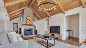 A spacious living room with a fireplace, a television, and a modern coffee table. - Charming ranch in Wilmington (Wilmington)