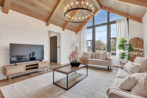 Amplia sala de estar con televisor grande, mueble de entretenimiento de madera y un sofá acogedor.