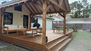 A covered patio with wooden furniture, a grill, and a view of the backyard. - Charming ranch in Wilmington (Wilmington)