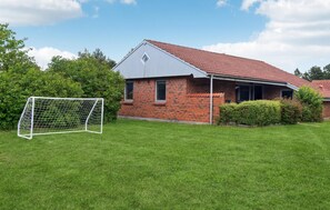 Ein Ziegelhaus mit rotem Ziegeldach, einer kleinen angebauten Garage und einem gepflegten Rasen.