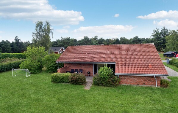 Ein Backsteinhaus mit rotem Ziegeldach, einer Veranda und einem Weg zum Eingang.