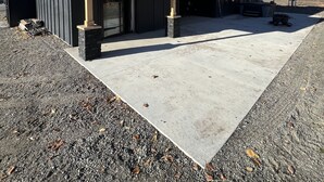Een modern gebouw met een overdekt buitengebied, een garage en een stenen pilaar.