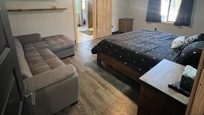 Een slaapkamer met een bed, een bank, een televisie en een plafondventilator.