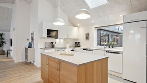 A modern kitchen with a central island, white cabinetry, and a large window providing natural light. - Nice home in Krakow am See with sauna (Krakow am See)