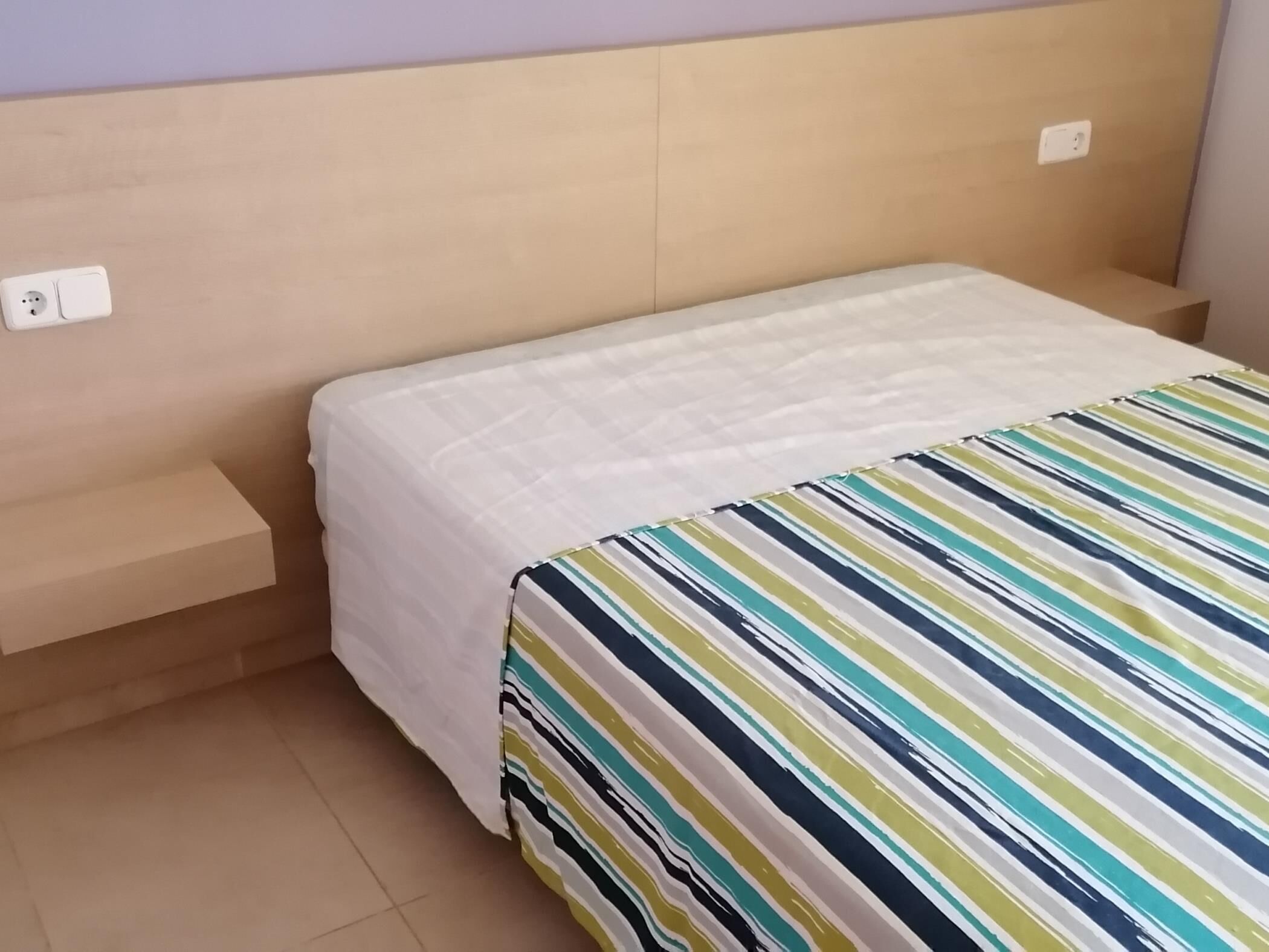 A bed with a white bedspread and a striped blanket.