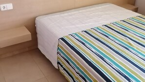 A bed with a white bedspread and a striped blanket. - Apartment 4/6 ground floor terrace (L'Estartit)