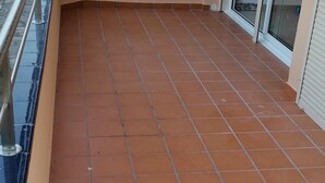 A tiled balcony with a metal railing and a window. - Apartment 4/6 ground floor terrace (L'Estartit)