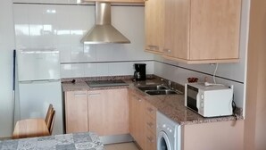 A compact kitchen with a built-in washing machine, a coffee maker, and a toaster. - Apartment 4/6 ground floor terrace (L'Estartit)