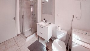 A bathroom with a glass-enclosed shower, a white sink with a mirror above it, and a toilet.